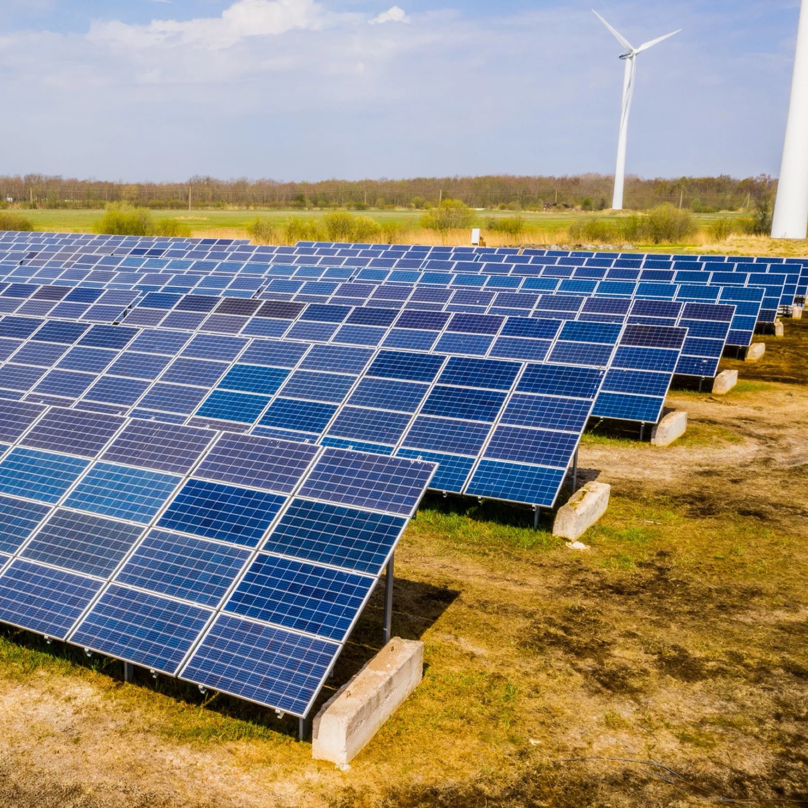 Solar panel field with wind turbines in the background